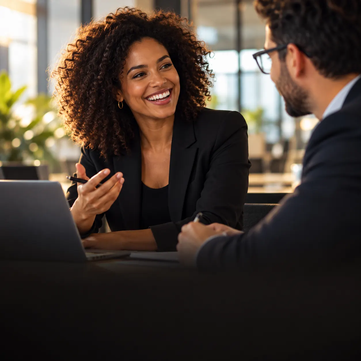 Colaboradora sorridente conversando com um colega em escritório moderno